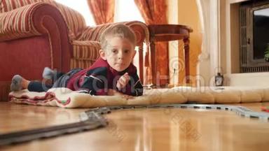 圣诞节早上，微笑的小男孩在客厅地板上玩玩具铁路和<strong>火车</strong>的视频。 <strong>儿童</strong>